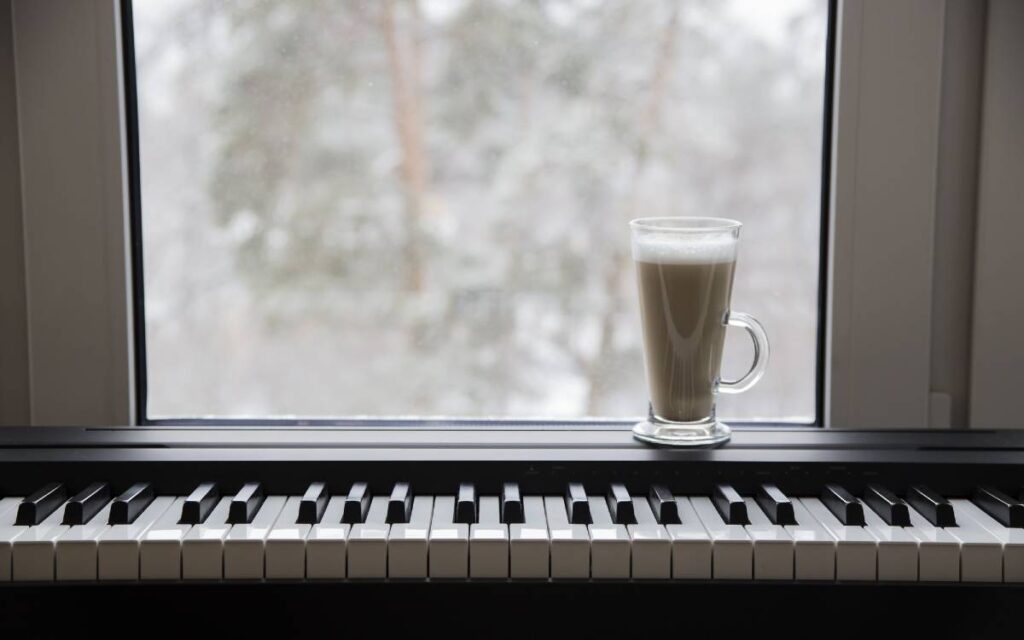 A glass of coffee on the piano near a window