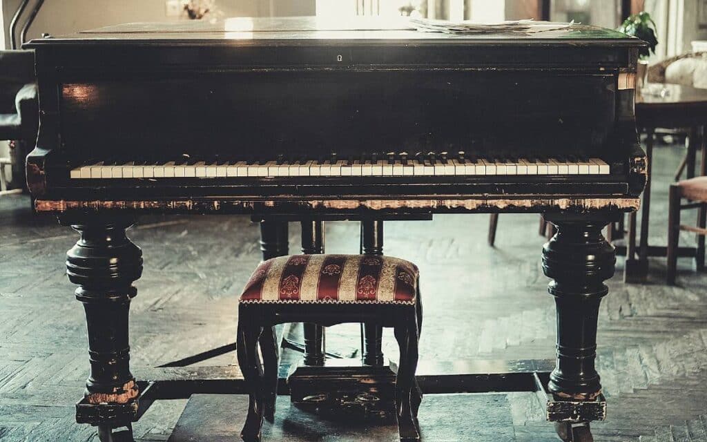 Old black grand piano with piano bench in front