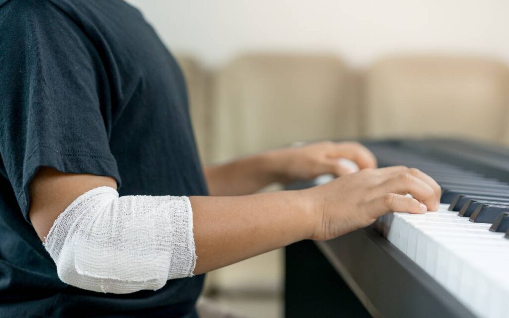 Boy playing the piano with a bandage on his elbow
