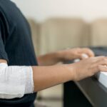 Boy playing the piano with a bandage on his elbow