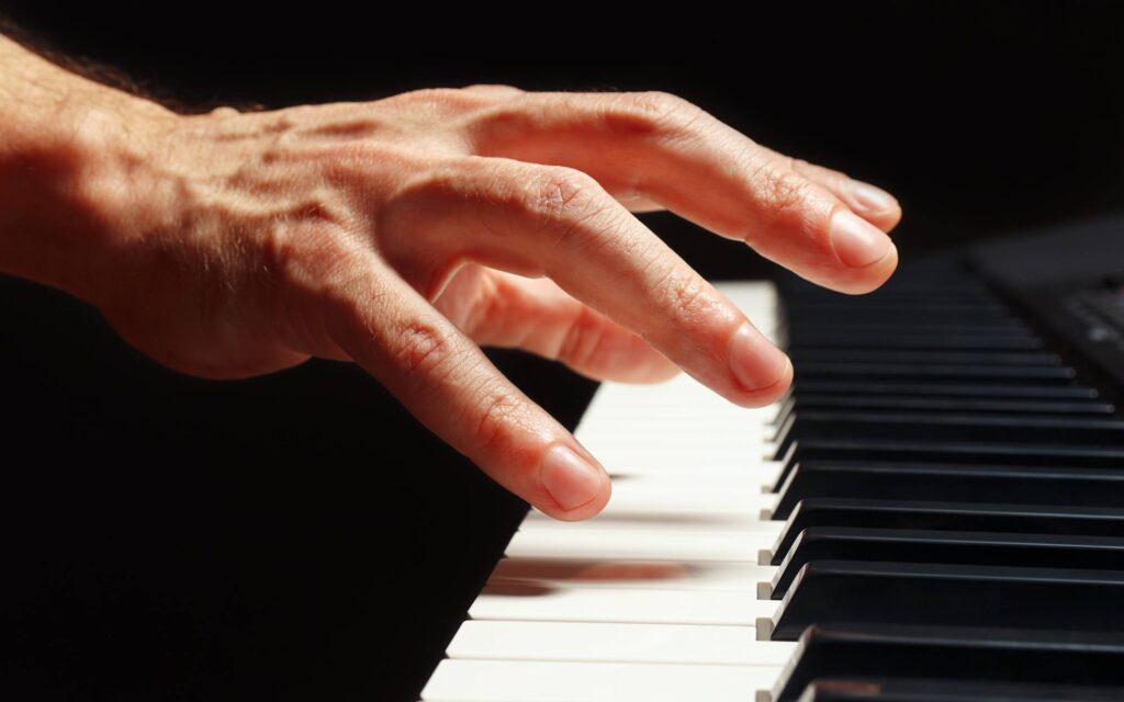 Hand of pianist over piano keys on a black background