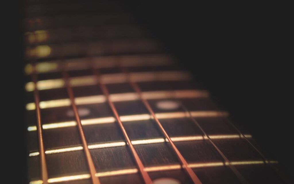 Closeup of guitar neck in diagonal position with strings in copper color on black background