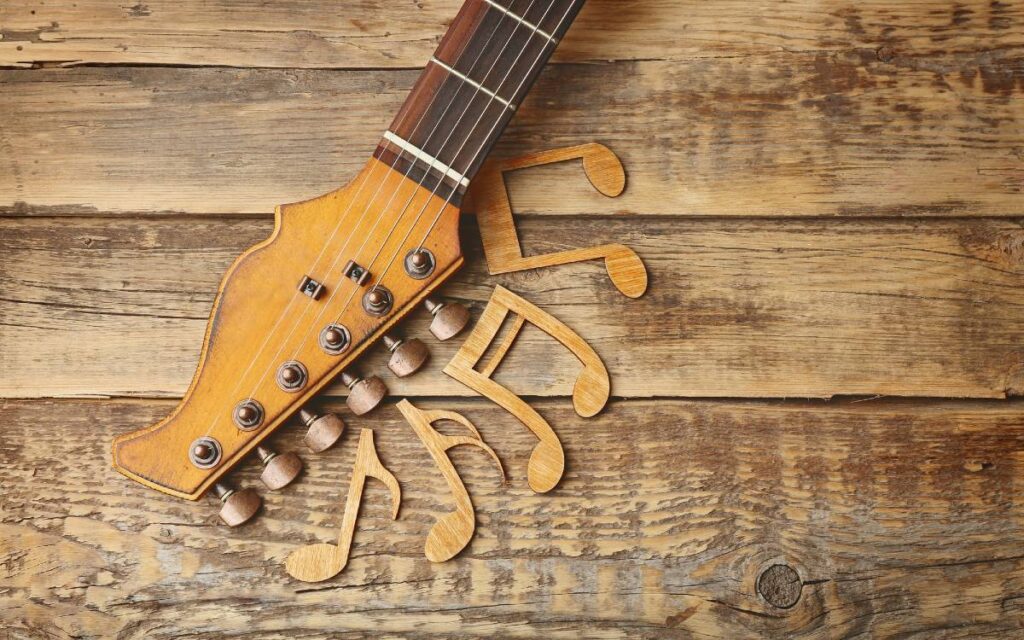 Guitar neck and music notes cutout on wooden background