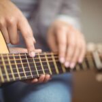 Guitar teacher giving lessons to pupil