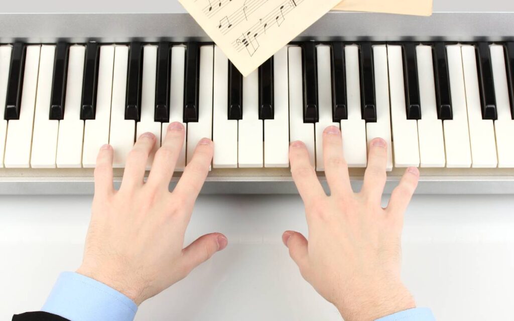 Hands of man playing piano on white table