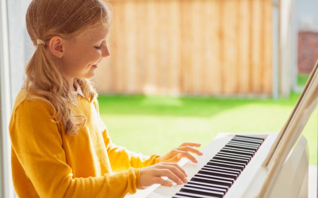 Little girl smiling while playing the piano