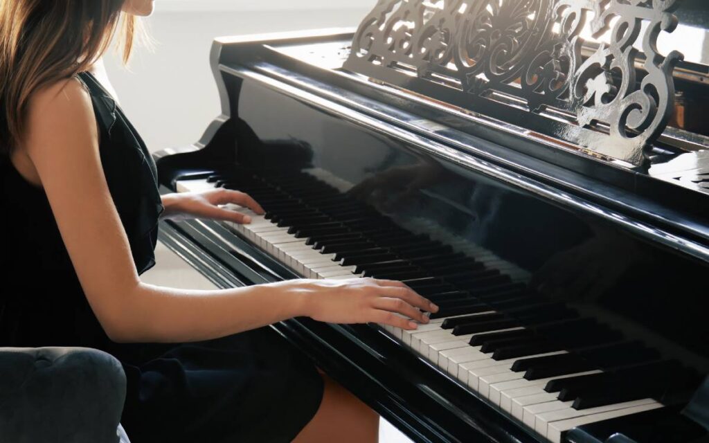 Woman sitting in front of the piano with hands on piano keys