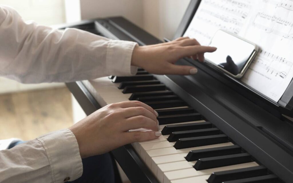 Female hand reaching out to touch a smartphone screen on a piano