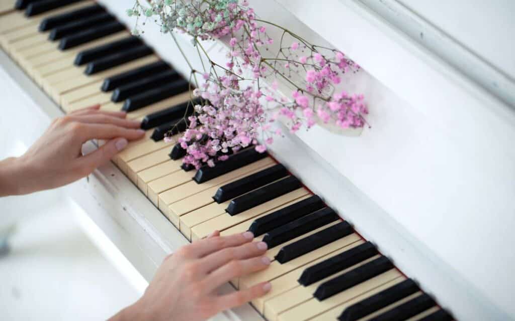 Female hands resting on piano keys adorned with small flowers