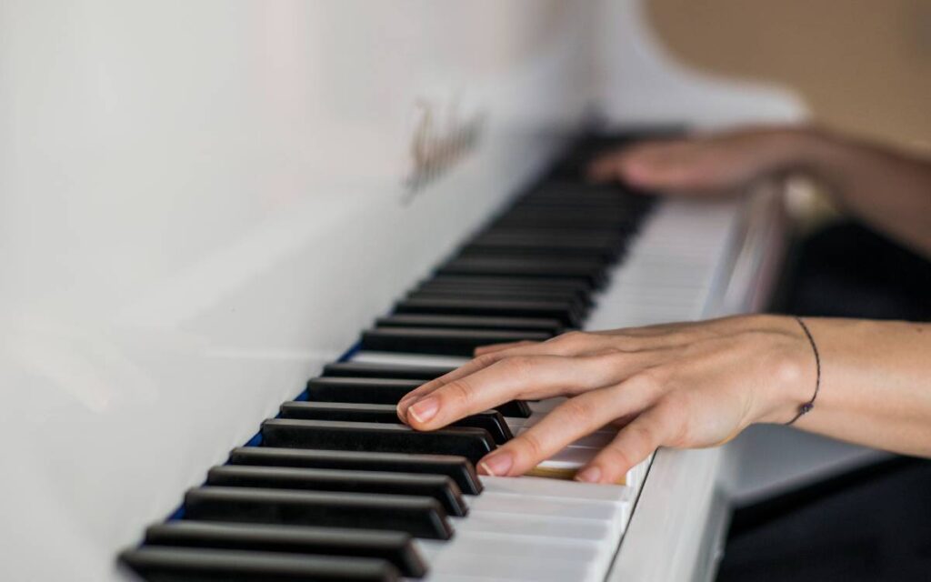Hands of a girl on a white piano