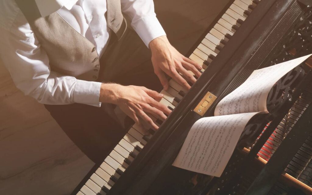 Man sitting in front of the piano with hands on the piano keys