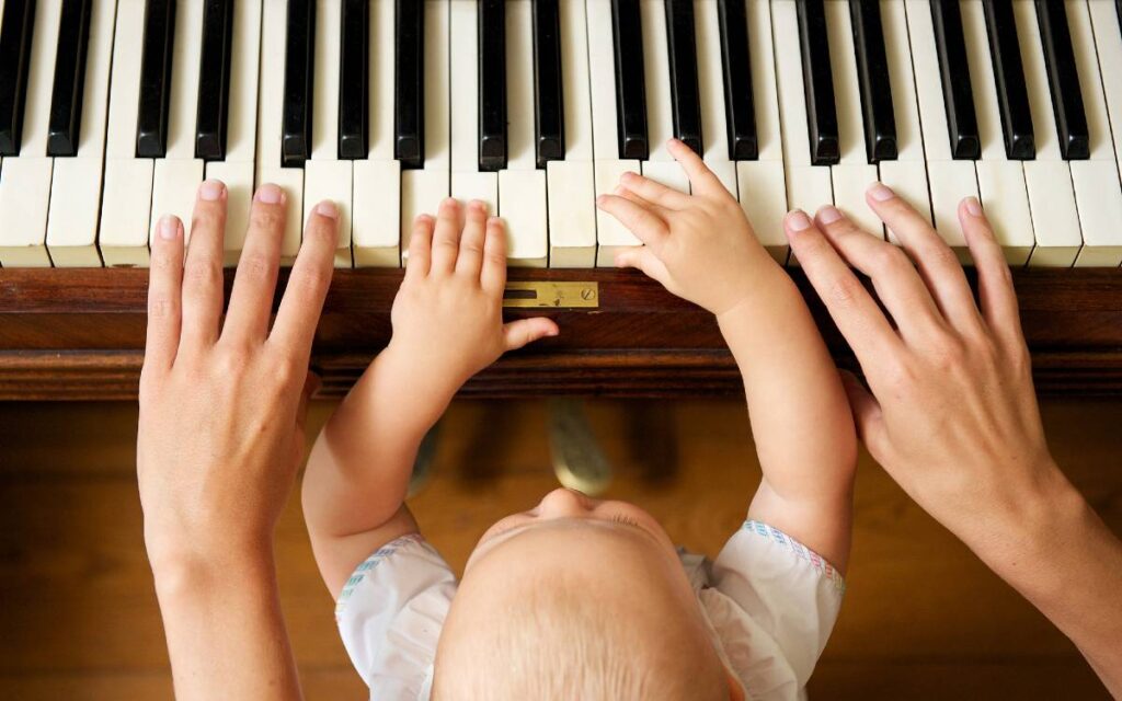 Mother and boy toddler's hands on piano keys