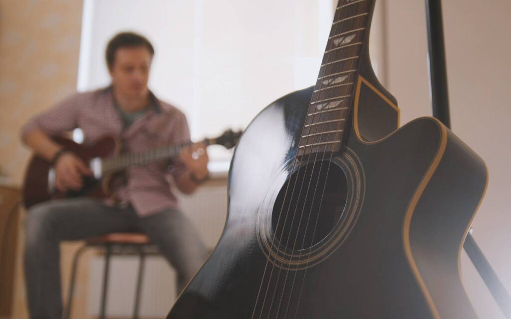 Acoustic guitar with blurred image of a man playing guitar in the background