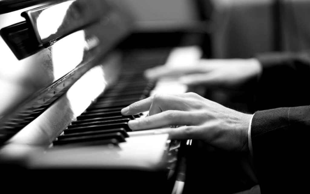 Black and white photo of man's hands on piano keys