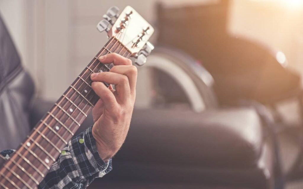 Close up of guitar neck with fingers of a man on guitar strings