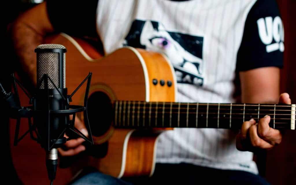 Close up shot of a male playing guitar, microphone in front