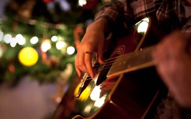 Easy christmas songs acoustic guitar_woman playing the guitar near a christmas tree