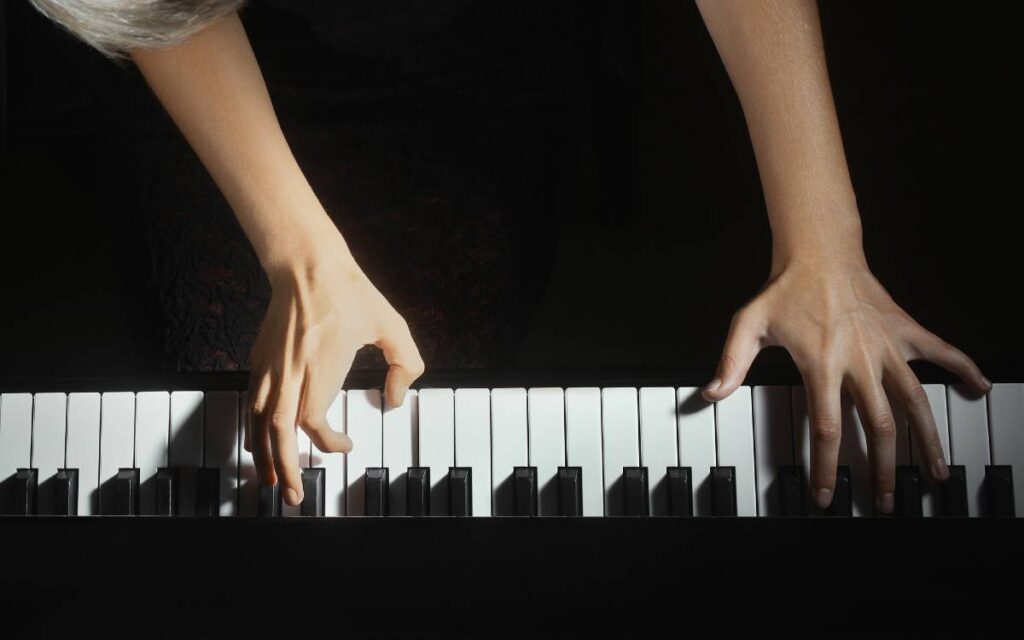 Female hands playing piano on a black background