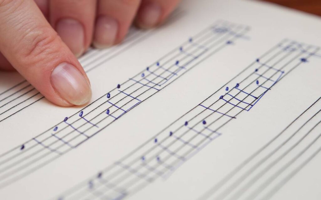 Finger pointing notes on a music sheet