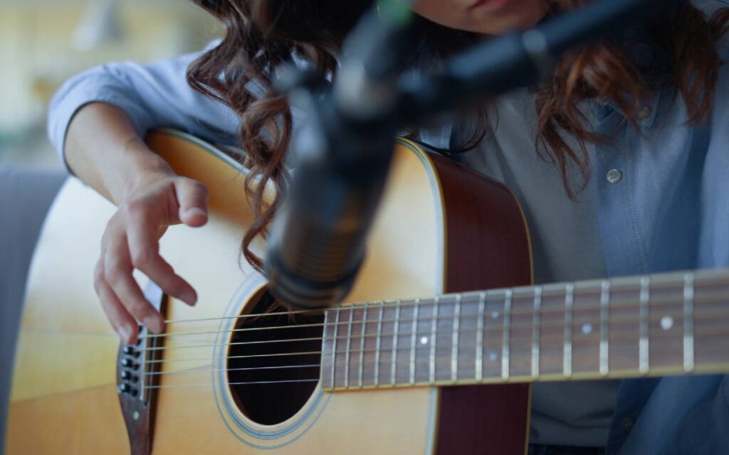 Girl playing guitar, microphone in front
