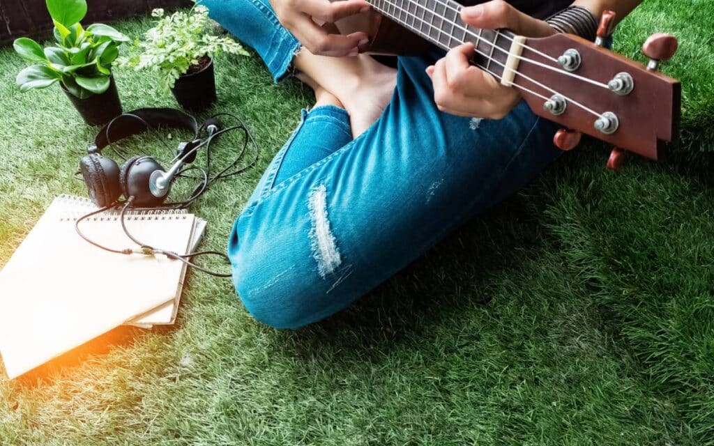 Girl sitting on grass playing ukulele