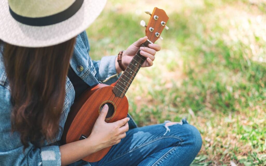 Girl sitting on grass playing ukulele