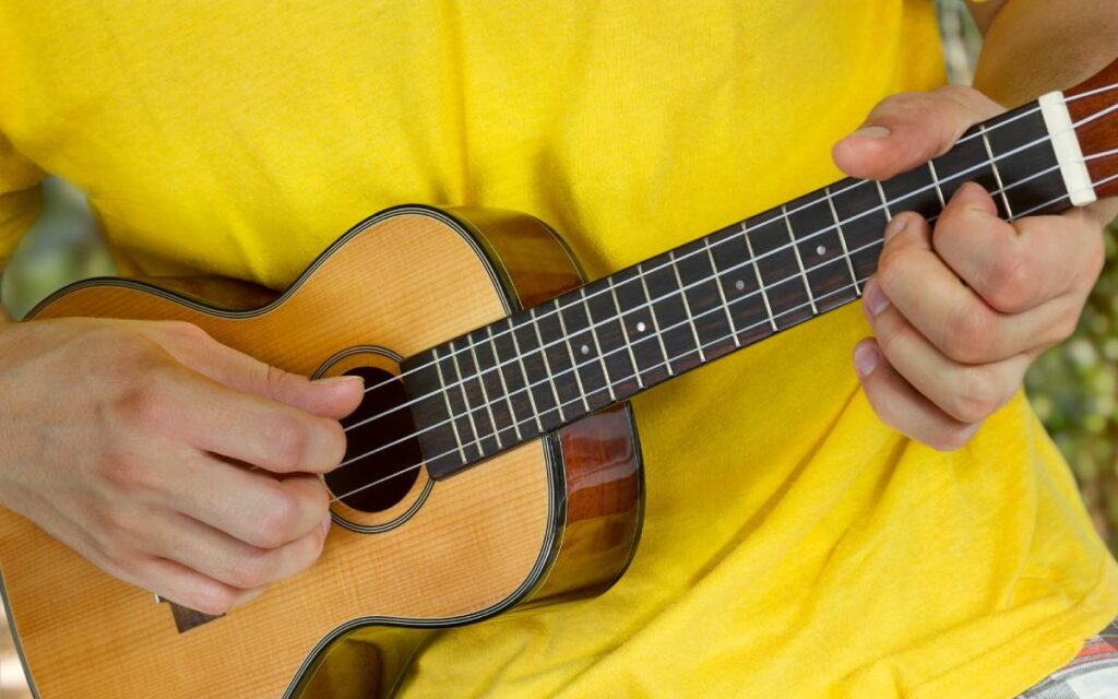 Man in a yellow t-shirt playing ukulele