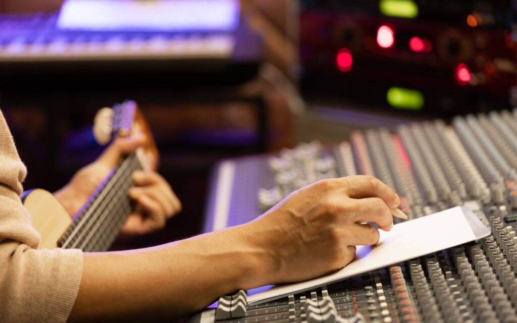 Man playing the guitar and writing a song in a recording studio