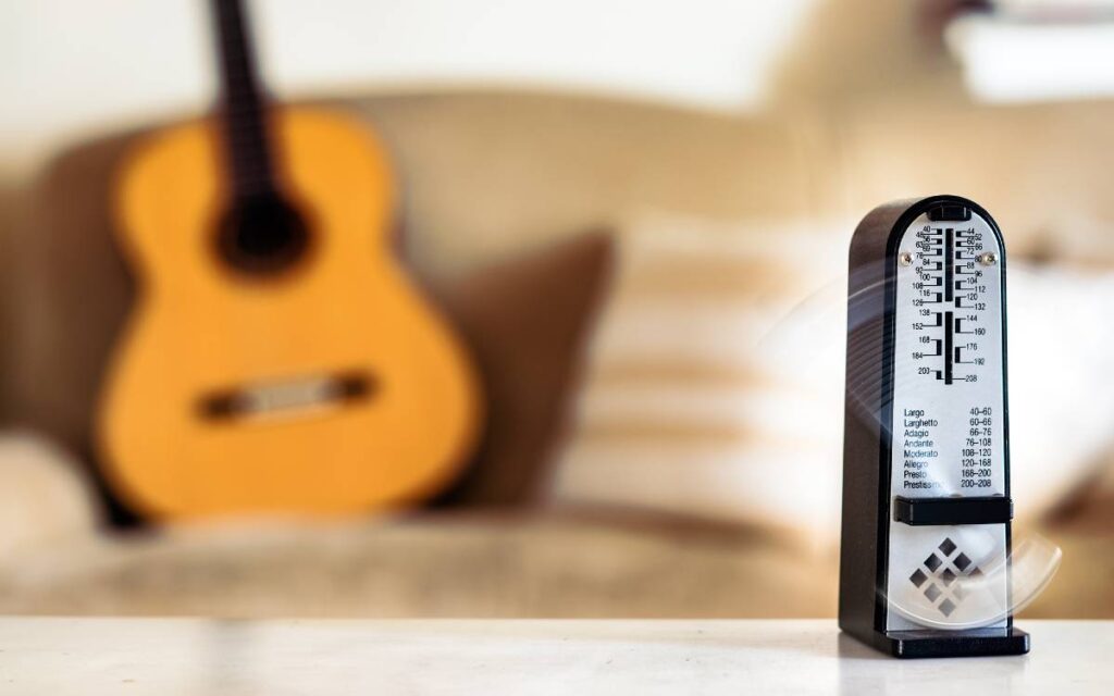 Metronome in motion with blurred image of a guitar in the background