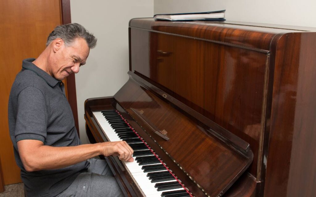 Middle aged man having fun while playing the piano at home