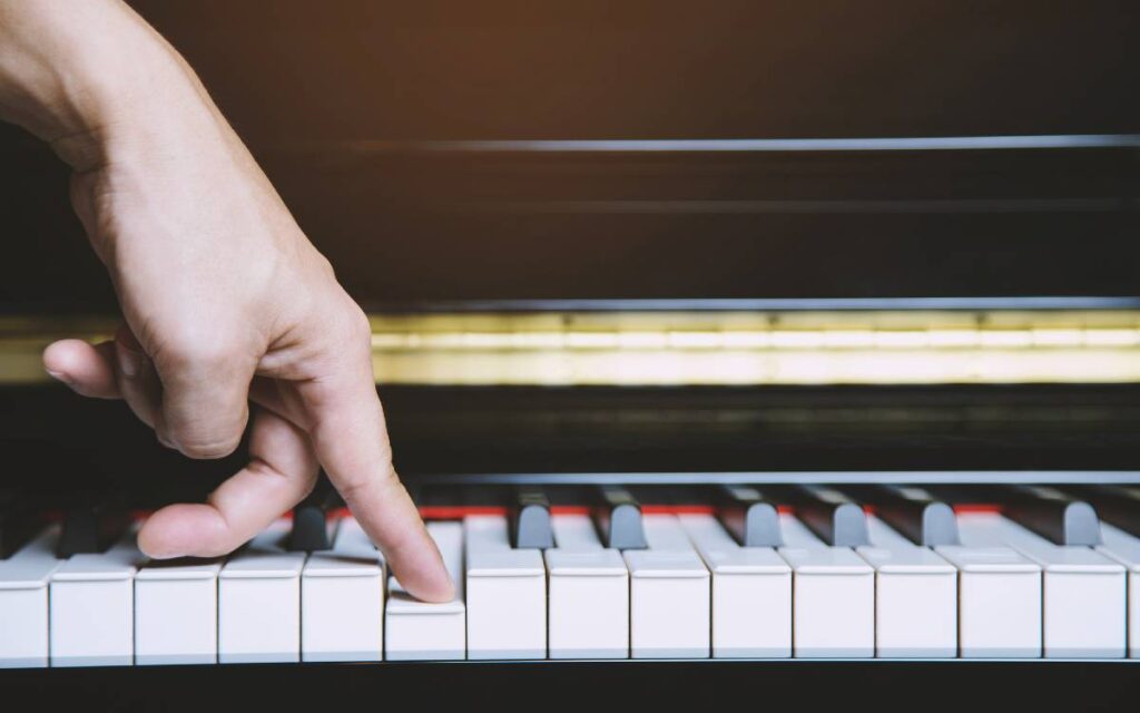 One finger pressing on white piano key