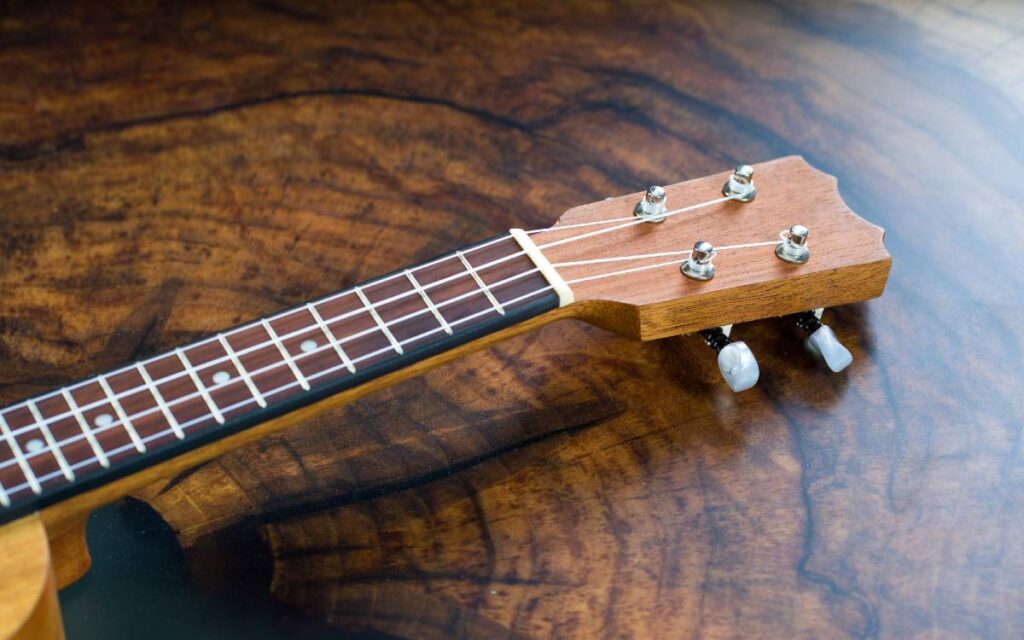 Ukulele on wooden floor close up of fretboard and headstock