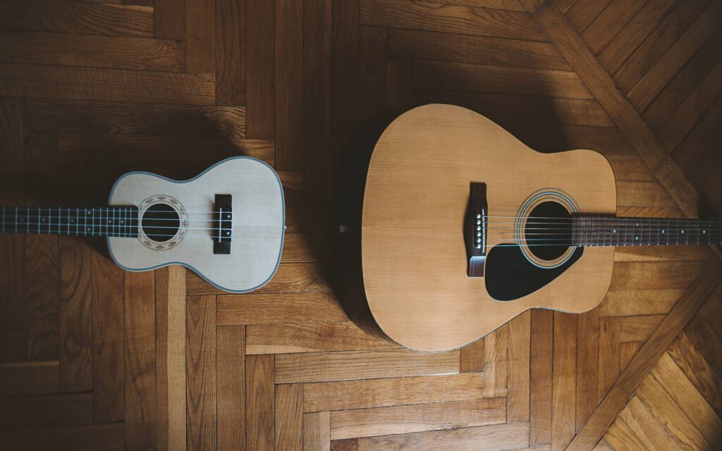 Top view of a guitar and ukulele on wooden floor