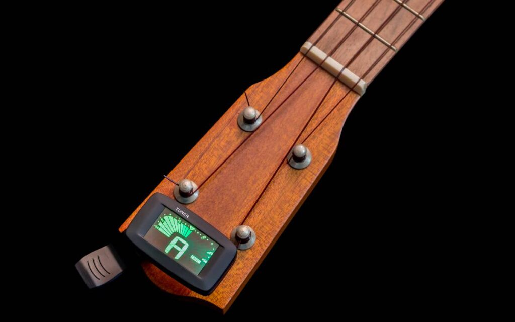 Ukulele with a clip-on tuner on black background