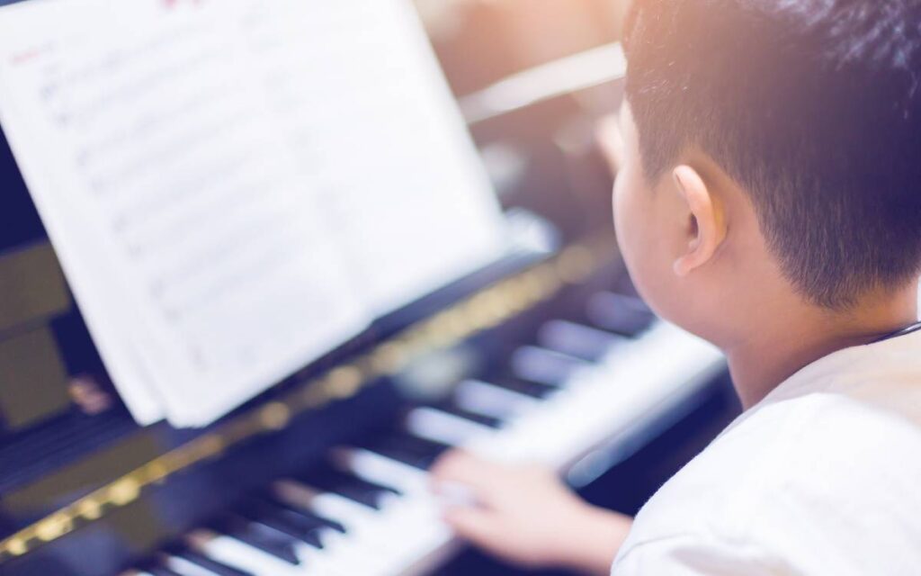 View of boy playing piano and reading sheet music