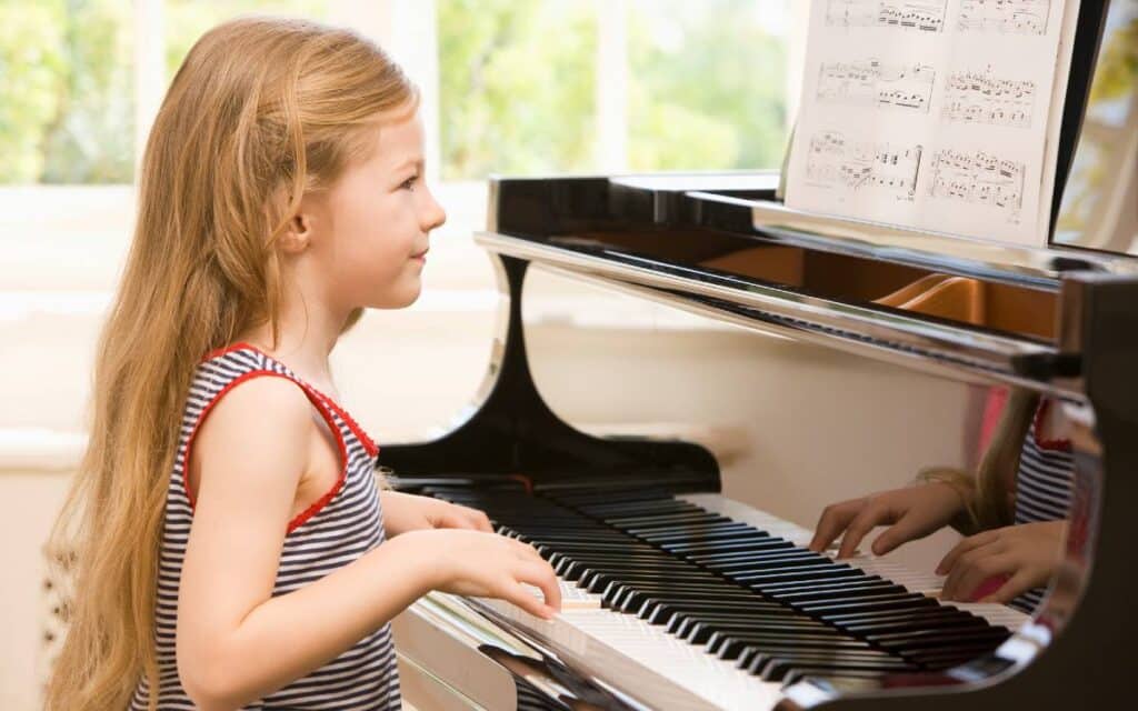Young girl reading sheet music and playing piano