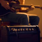 Close up of a guitar amp with a man playing acoustic guitar on the background