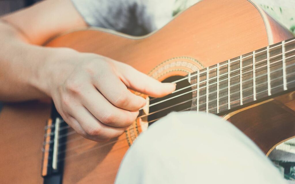 Close up of a man's hand on guitar strings