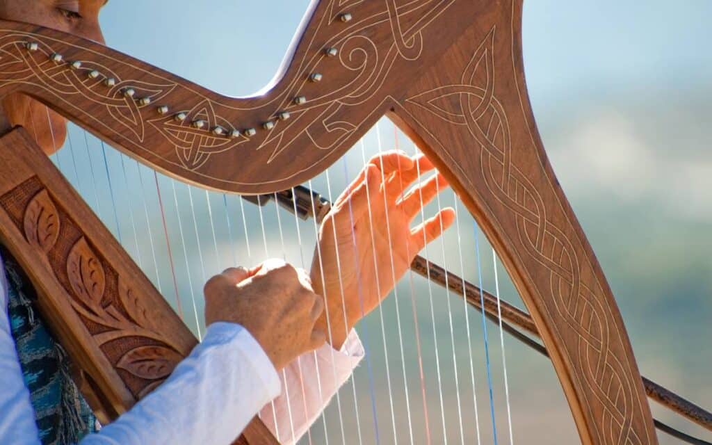 Close up of hands playing harp, one of the hardest instruments to play