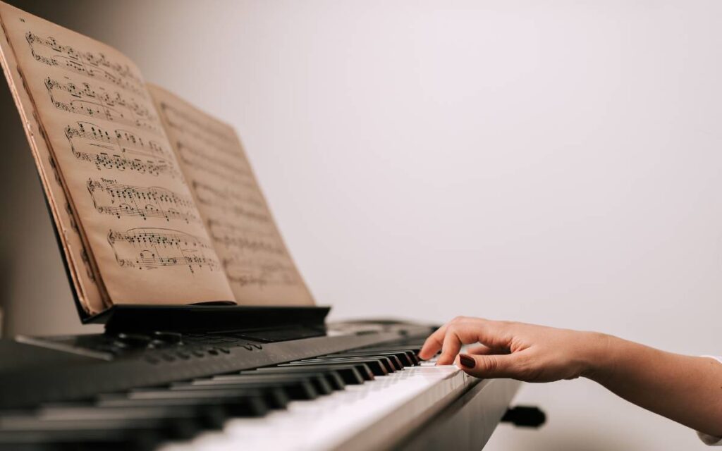 Close up of music sheet on the piano, woman's hand on piano keys