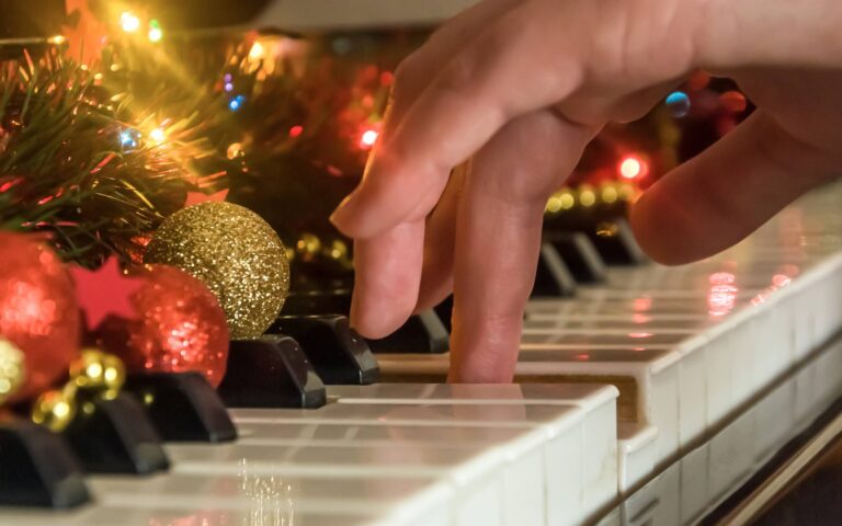 Easy piano christmas songs_hand playing the piano decorated with christmas decorations