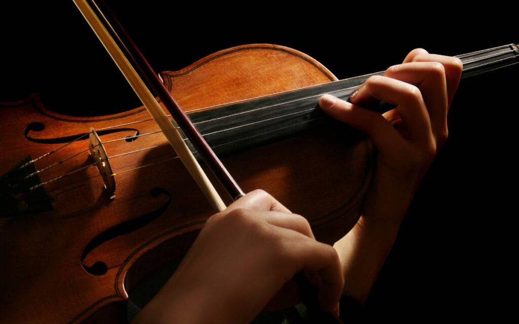 Hands of woman playing violin on black background