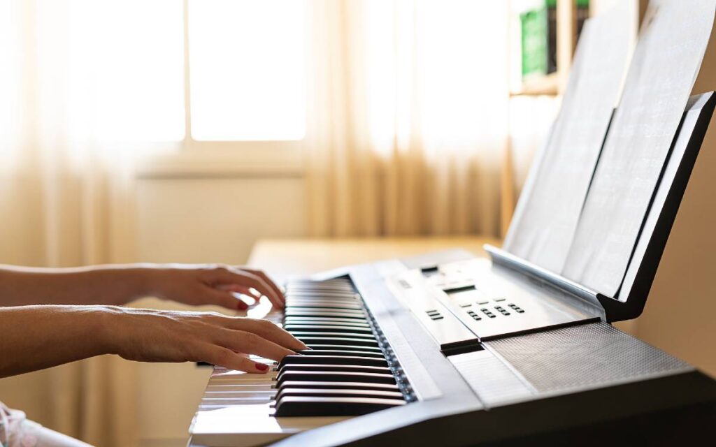 Hands playing piano near window