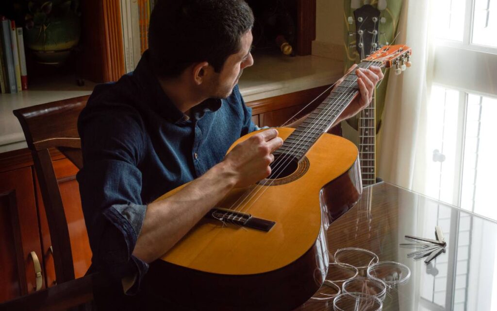 Man changing acoustic guitar's strings