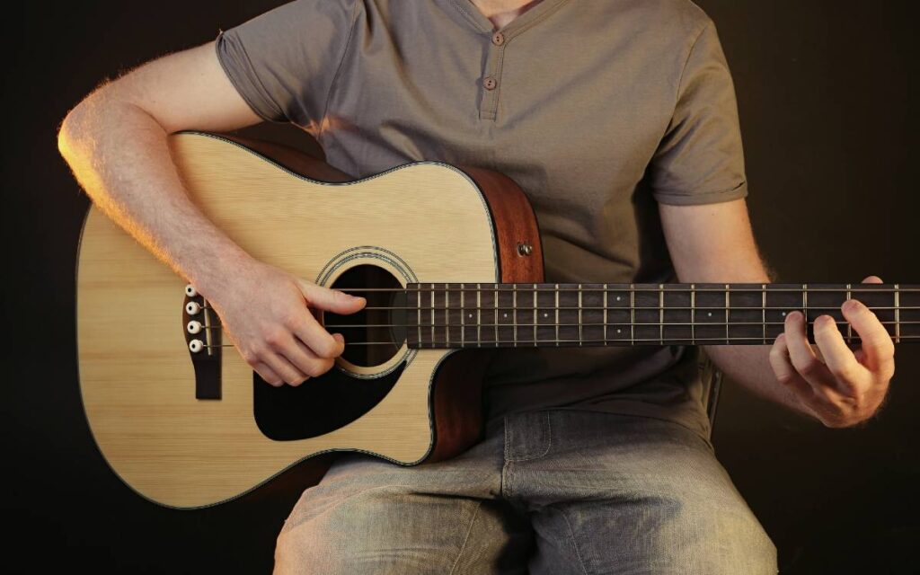Man playing acoustic guitar on black background