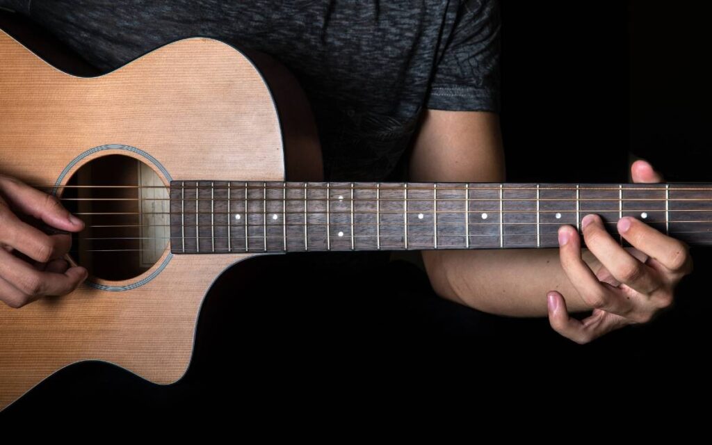 Man playing acoustic guitar on black background