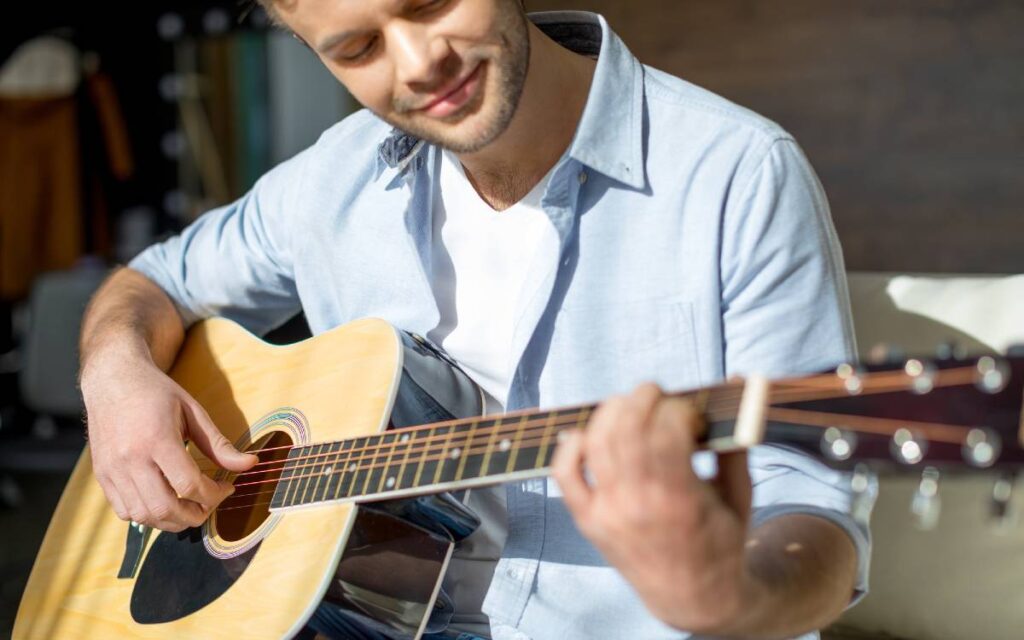 Man smiling while playing acoustic guitar