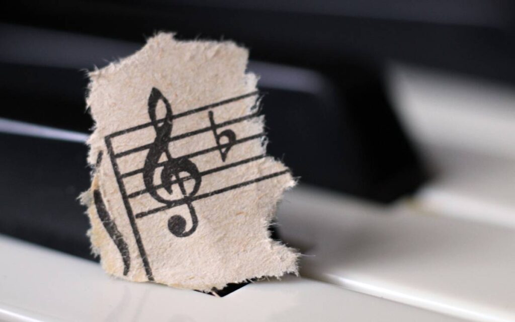Torn piece of sheet music with treble clef symbol on piano keys