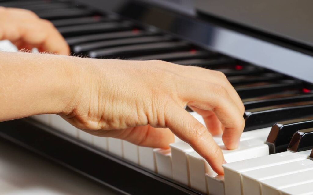 Close-up of boy's hand playing the piano