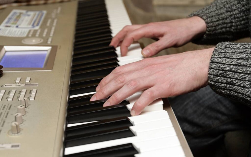 Close-up shot of man's hands playing digital piano